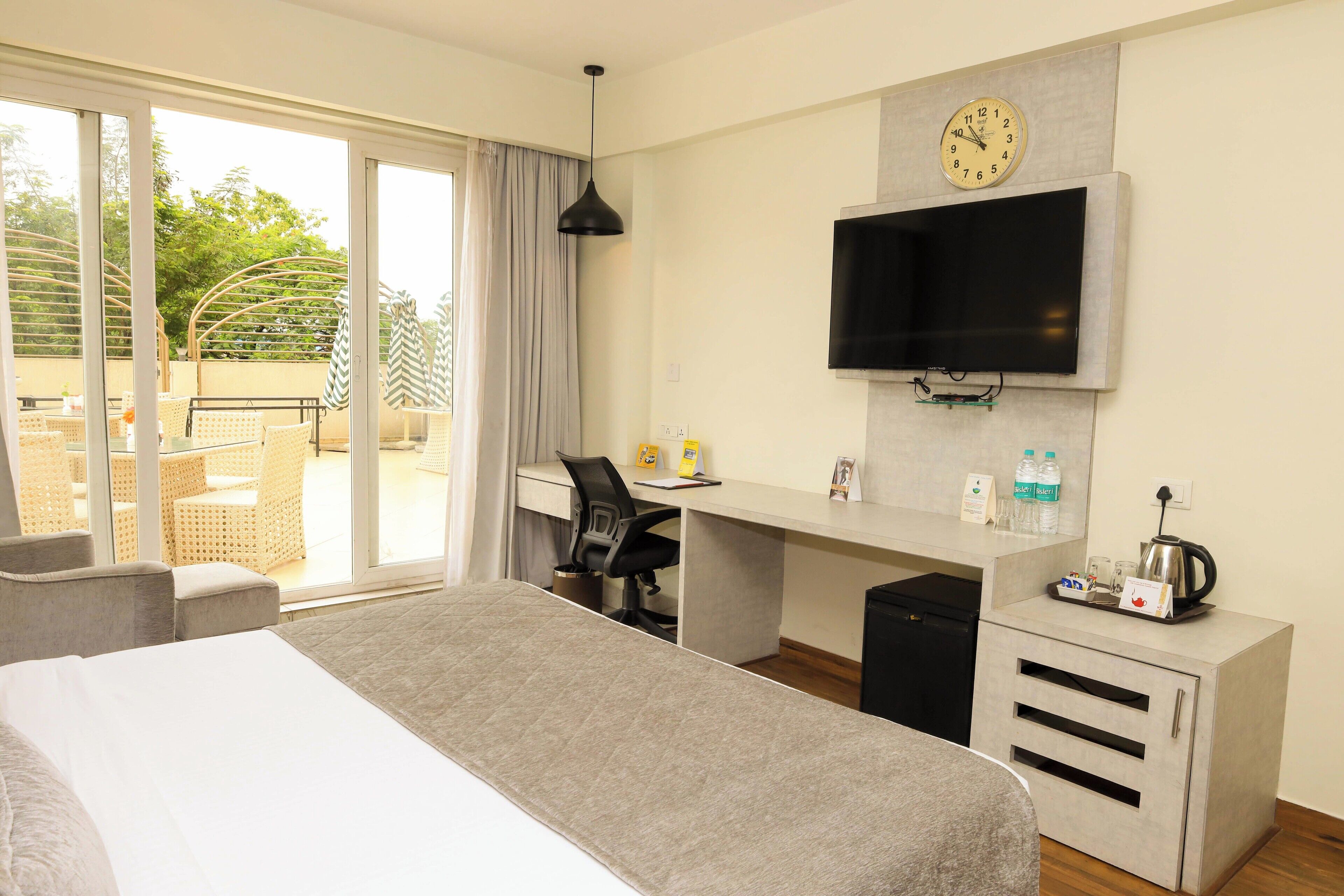 Una habitación de hotel con cama, escritorio, televisión y vistas al exterior.