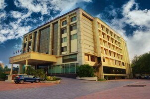 Un hotel de varios pisos con una fachada moderna, un acceso cubierto y una zona de estacionamiento.