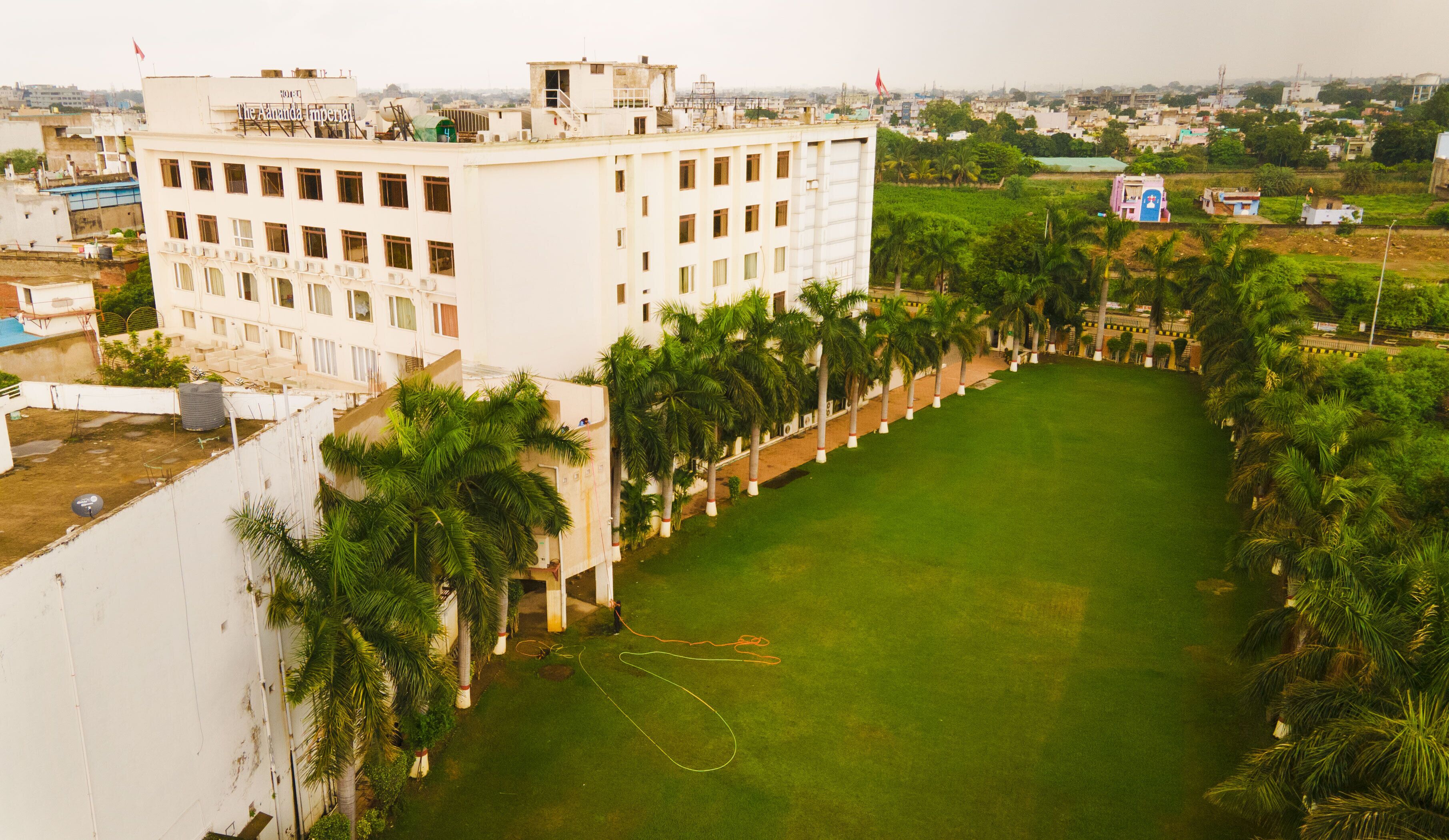 A large building with multiple floors, surrounded by a well-maintained lawn and palm trees.