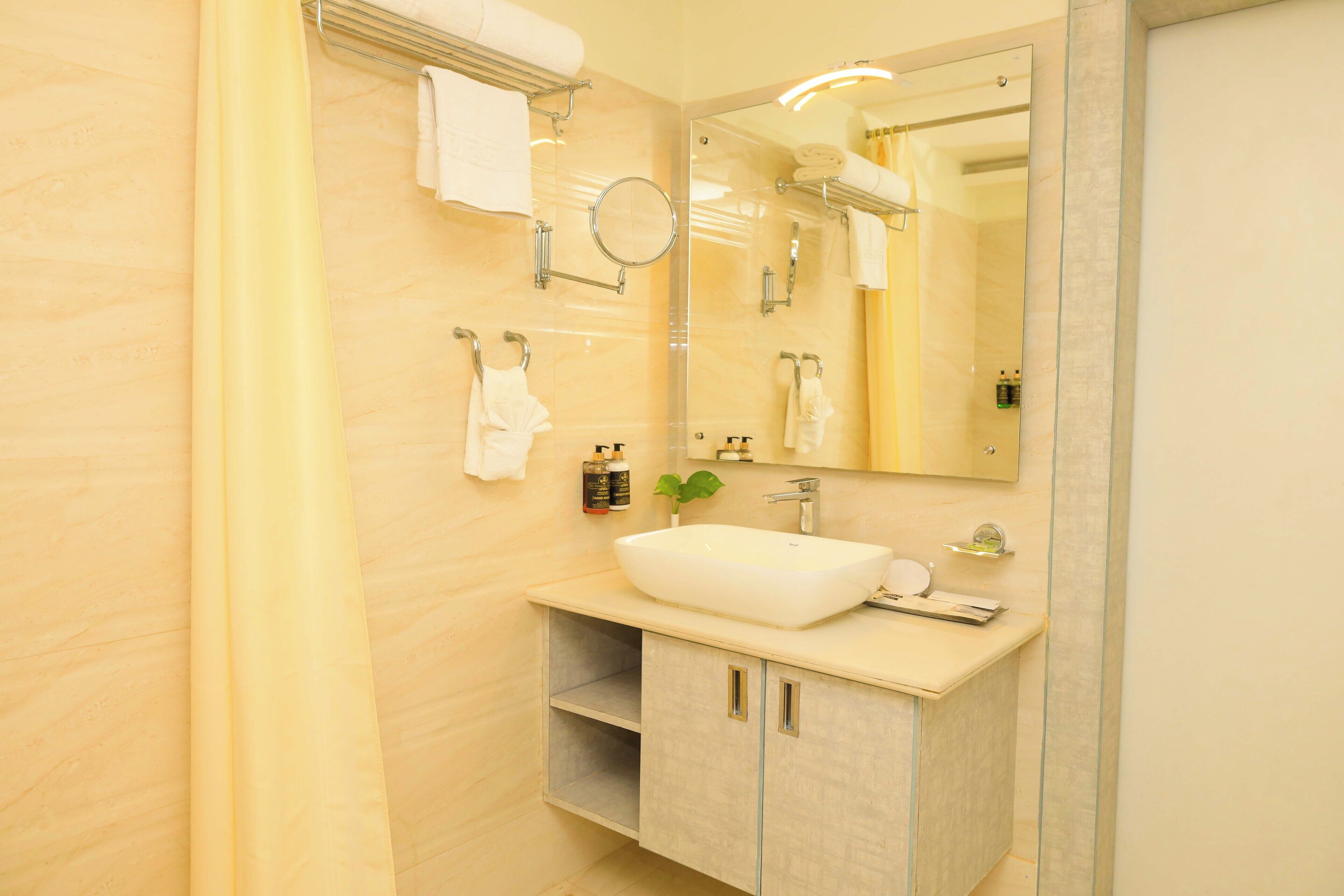 A modern bathroom with a large mirror, white sink, and towel rack.