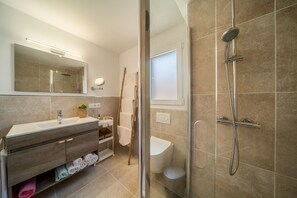A modern bathroom with a glass shower enclosure, a vanity with a sink and mirror, and a toilet.