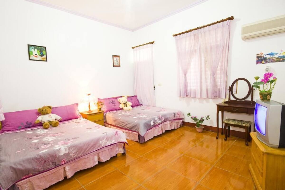 A bedroom with two beds, a TV, and a desk.