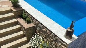 Une piscine avec des marches en pierre et des parterres de fleurs.