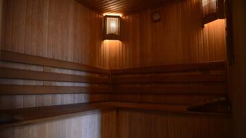 A wooden sauna with benches and a small wall-mounted heater.