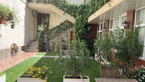 Une cour avec une table en bois, deux jardinières ornées de fleurs jaunes, un escalier et un mur en briques.