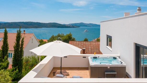 A rooftop terrace with a hot tub, outdoor seating, and a view of a lake and mountains. - Villa Marulovo (Okrug)