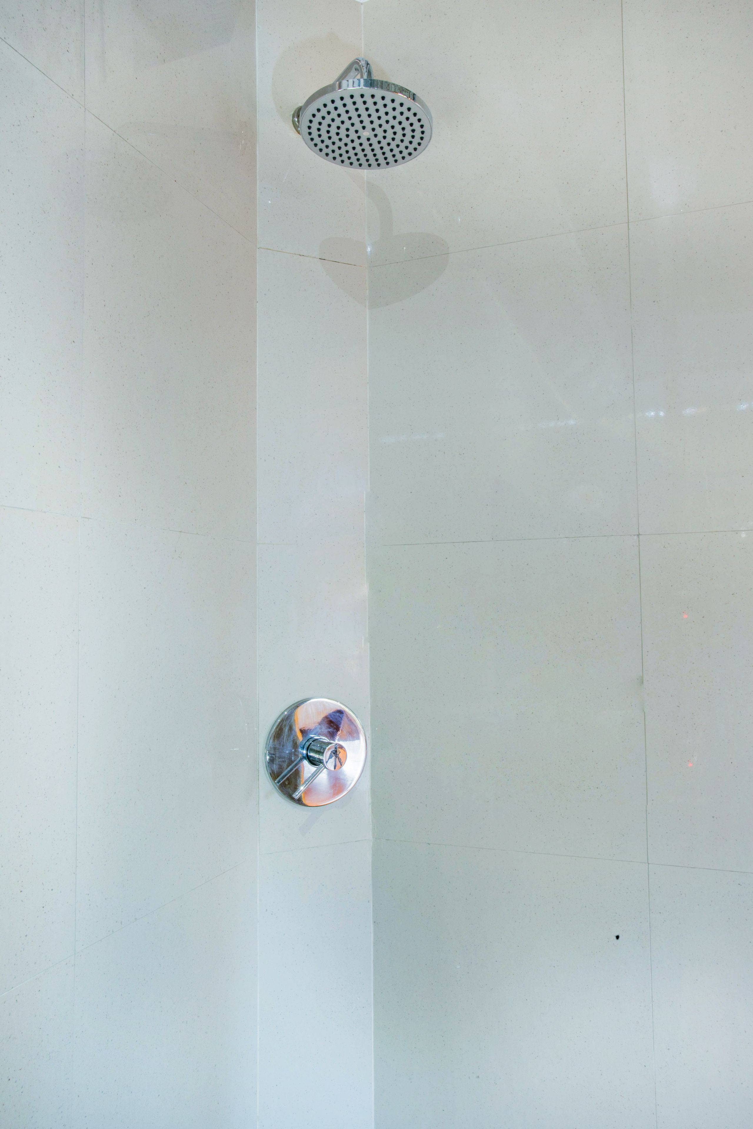 A tiled floor with a showerhead and a circular object, possibly a light fixture.