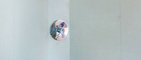 A tiled floor with a showerhead and a circular object, possibly a light fixture.