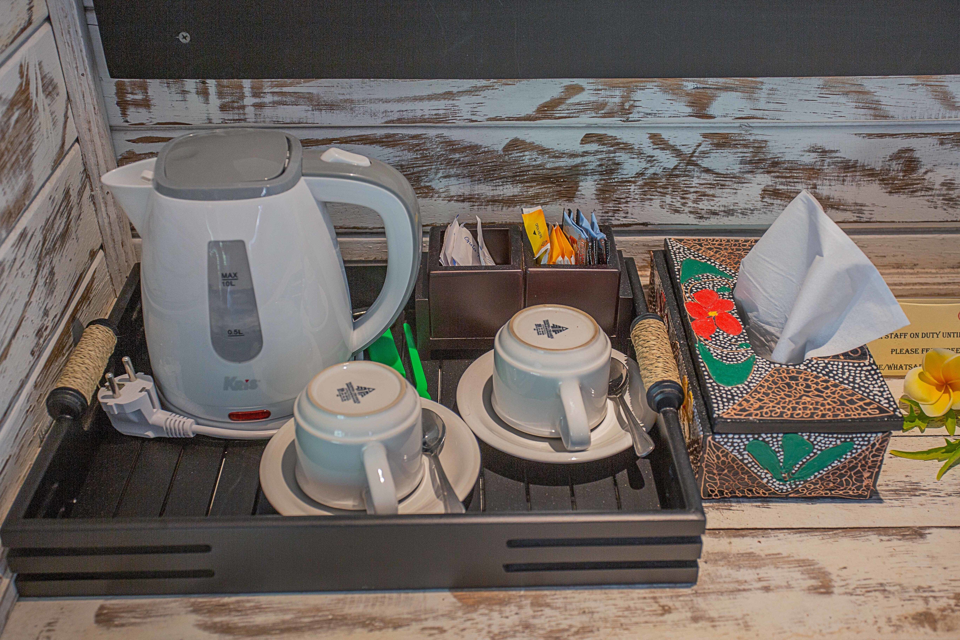 Ein Tablett mit einer Kaffeemaschine, zwei Tassen, einem Taschentuchgebinde und einem dekorativen Gegenstand.