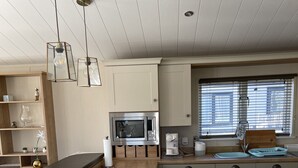 Een moderne keuken met een houten aanrecht, inbouwmeubels, een magnetron en een raam met jaloezieën.