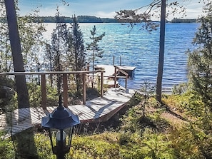 A wooden deck with a bench and a table overlooking a calm lake, surrounded by trees. - Mäntyniemi by Interhome (Rääkkylä)