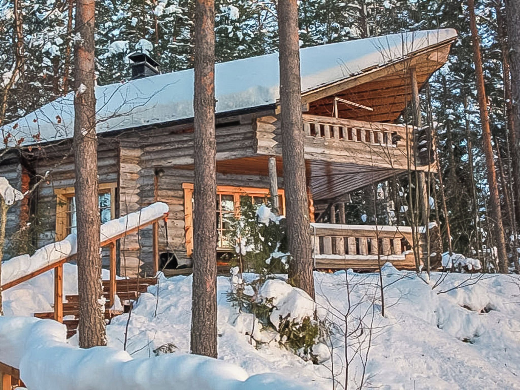 A log cabin with a balcony and a staircase leading to the entrance.
