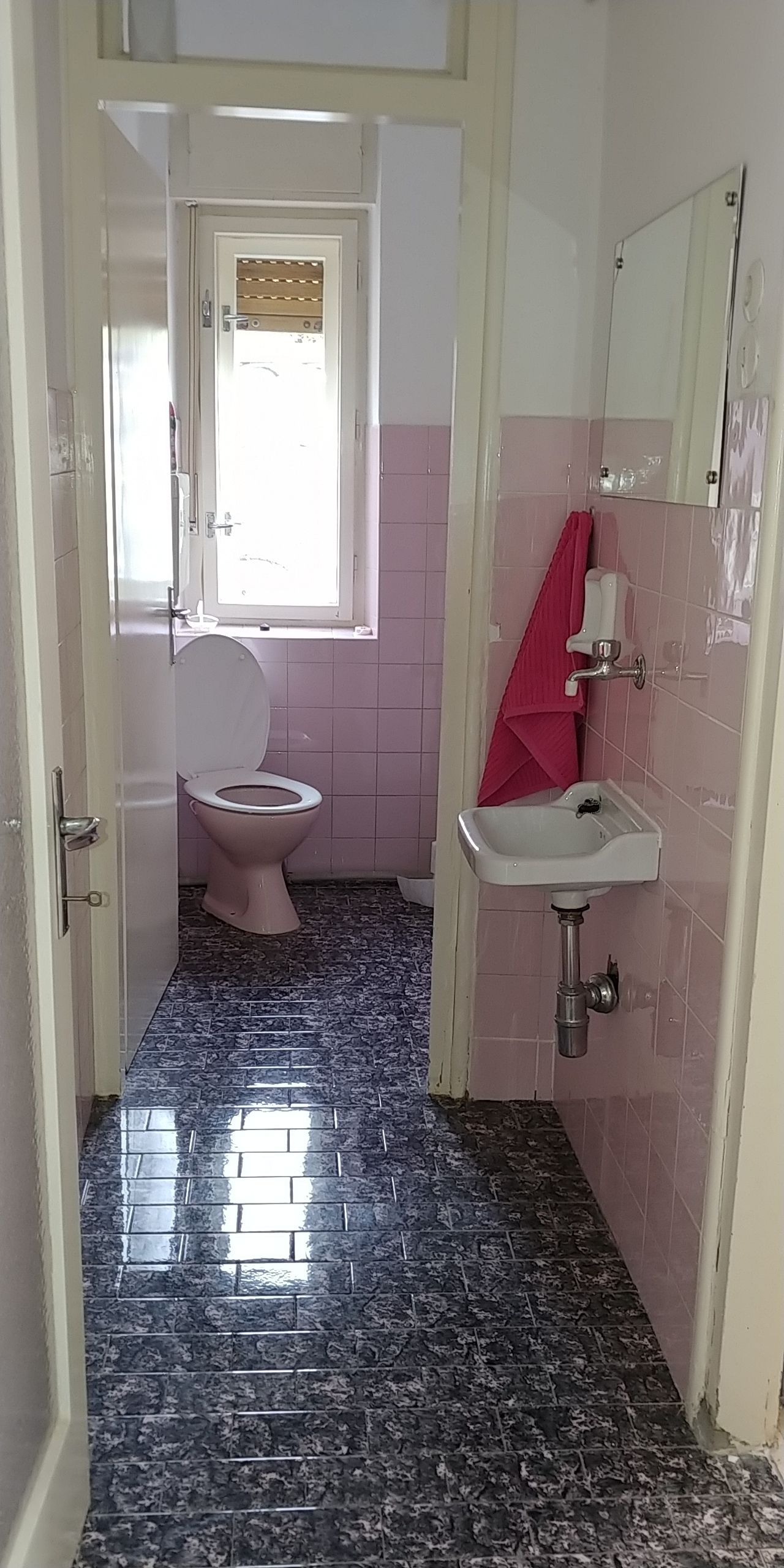 Un baño con inodoro, lavamanos y ventana.