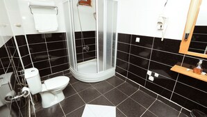 Een badkamer met douche, toilet en wastafel.
