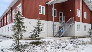 A red building with a covered entrance and a staircase leading to the main entrance.
