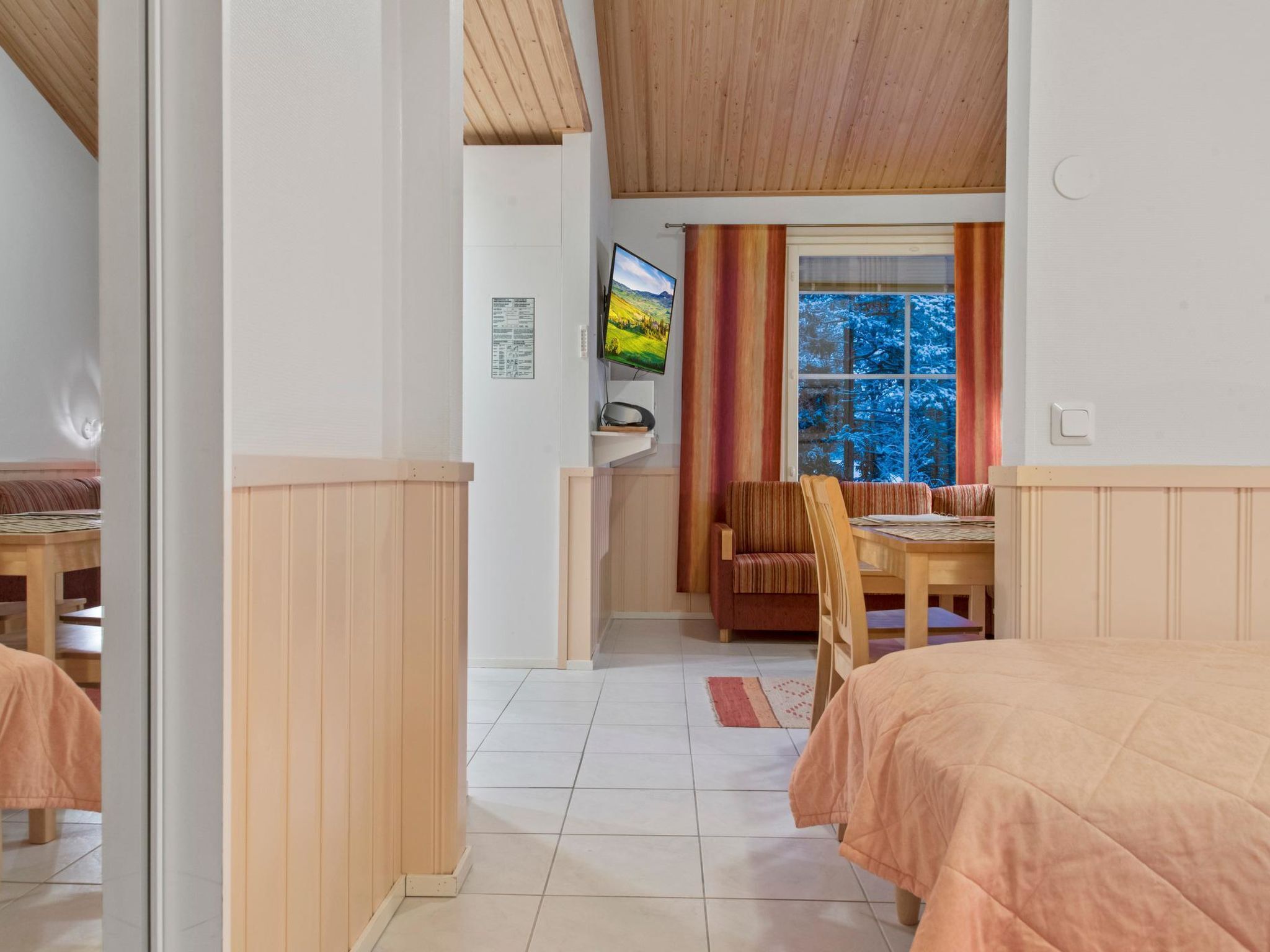 Een kamer met een bed, een bureau en een stoel. Er is een raam met uitzicht op bomen.