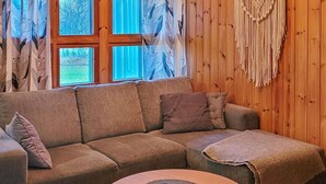 A cozy living room with a wooden wall, a sofa, and a macrame wall hanging.