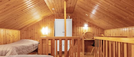 Ein Schlafzimmer im Holzbau mit zwei Betten, einer Holztreppe und einem weißen Kleiderschrank.