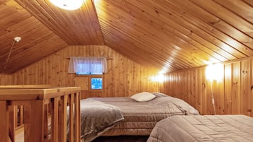 Een gezellig slaapkamer onder de dakpannen met houten wanden, een schuine hemel, een bed, een nachtkastje en een raam met uitzicht op bomen.