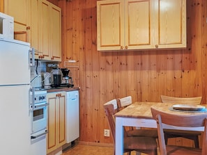 A compact kitchen with wooden cabinets, a white refrigerator, a stove, and a coffee maker. - Ylläskarpalo 3 päätyhuoneisto by Interhome (Äkäslompolo)