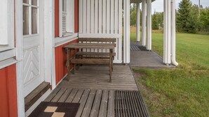 A wooden porch with a bench and a rug.