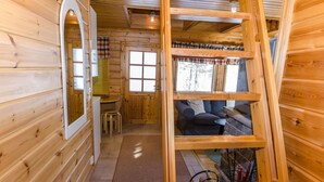 L’intérieur d’une cabane en bois comprend un lit en mezzanine, un coin repas et une cheminée.
