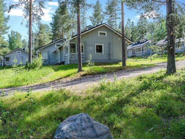 A row of cabins with a dirt path leading to them, surrounded by trees.