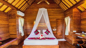 A wooden cabin room with a bed, a desk, and a chair. - Pancali Cottages (Lembongan Island)