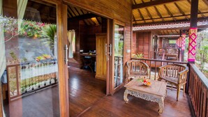 A wooden-floored room with a balcony, wooden furniture, and a glass door leading outside. - Pancali Cottages (Lembongan Island)