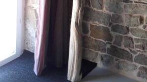 A room with a stone wall, a wooden sculpture, and a curtain.