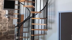 A spiral staircase with wooden steps and black railings, leading to an upper floor.