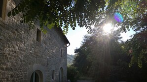 A stone building with arched doorways, outdoor seating, and a car parked nearby.