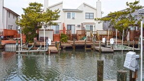 A waterfront property with docked boats, wooden docks, and a house with a chimney.