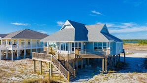 A beachfront property with a large house featuring multiple decks and a covered porch. - Beachfront | Pet Friendly | Gulf and Lagoon Views (Gulf Shores)