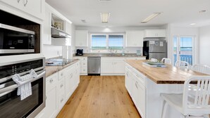 A modern kitchen with white cabinetry, stainless steel appliances, and a wooden island. - Beachfront | Pet Friendly | Gulf and Lagoon Views (Gulf Shores)