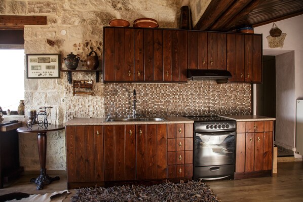 Une cuisine rustique avec des meubles en bois, un dosseret carrelé et une cuisinière en acier inoxydable.