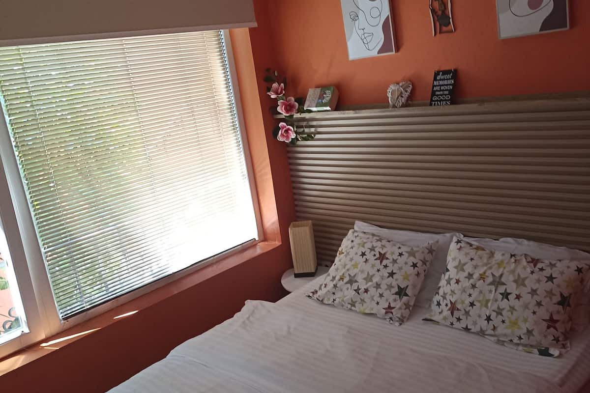 Un dormitorio con cama, ventana con persianas y una obra de arte en la pared.
