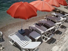 Mobiliario exterior con sombrillas y sillones de descanso sobre grava.