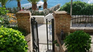 Una entrada con puerta metálica y vista al mar, con un puente al fondo.