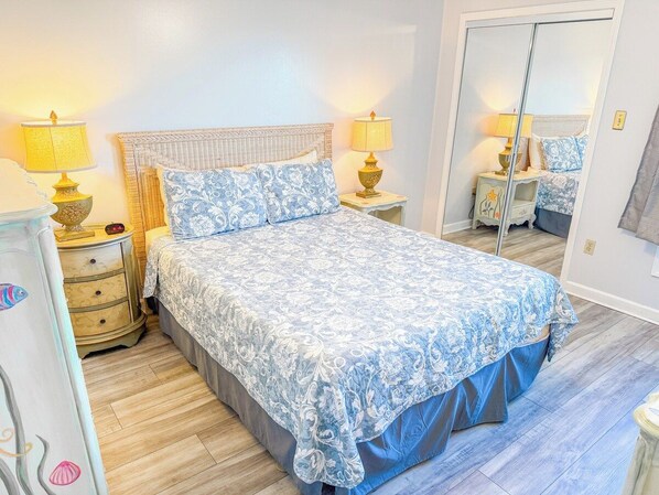A bedroom with a bed, bedside tables, lamps, a dresser, and a mirror. - Inlet Point Villas 4C (North Myrtle Beach)