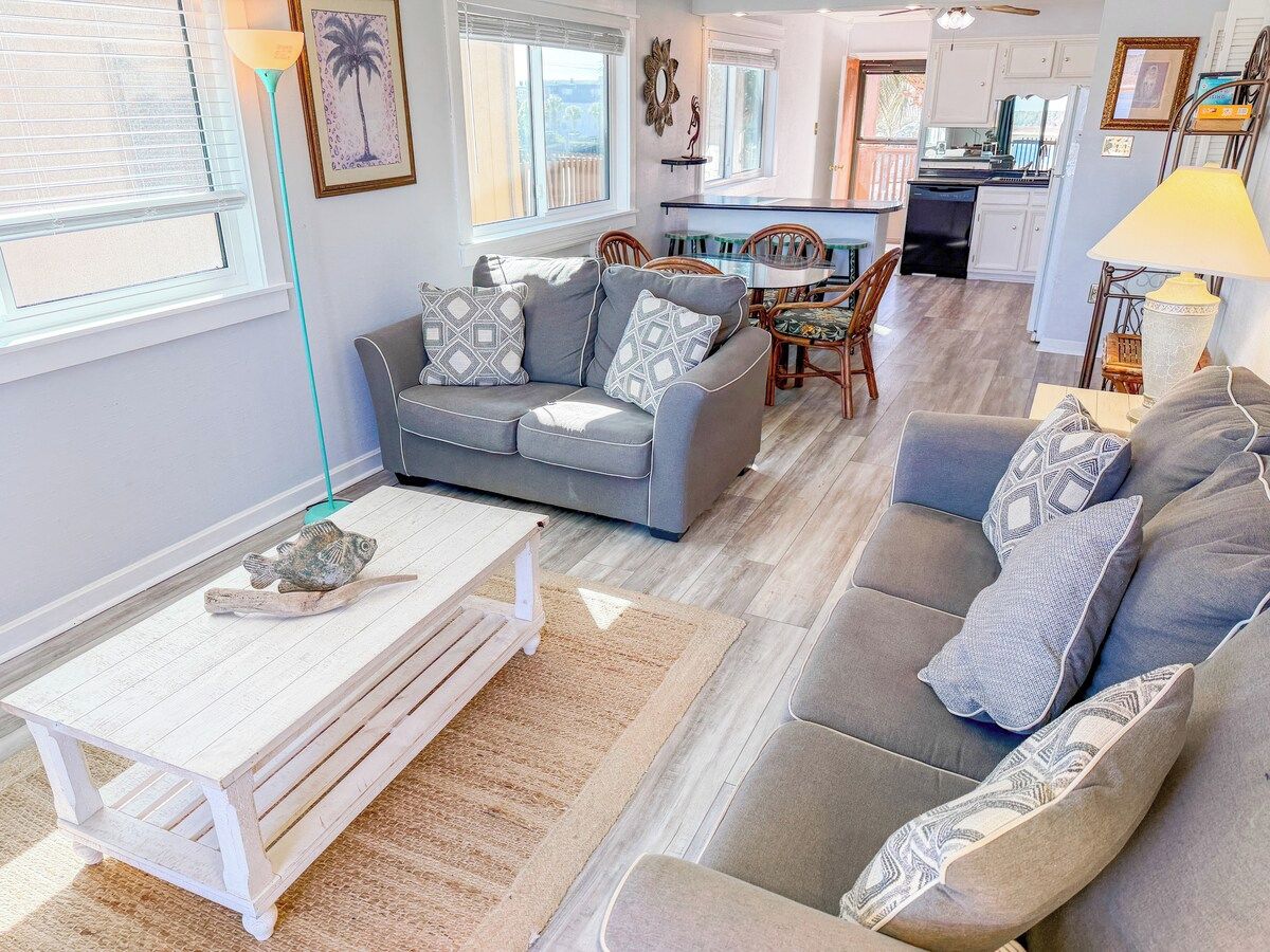 A living room with a sofa, a coffee table, and a dining area with chairs and a table.