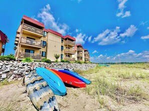 A beachfront property with a multi-story building, a rocky shoreline, and colorful kayaks. - Inlet Point Villas 4C (North Myrtle Beach)