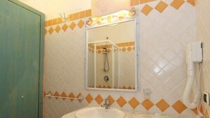 Un baño con lavamanos, espejo y un perchero para toallas.