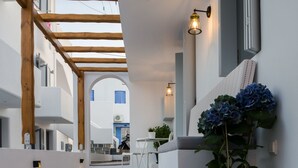 Un interior modern amb sòl de formigó, bigues de fusta, zona d'estar amb taula i cadires, i una planta en test.