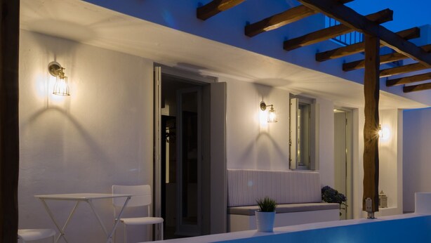 Zona d'estar exterior moderna amb piscina, parets blanques i una pèrgola de fusta.
