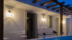 Un área de estar moderna al aire libre con piscina, paredes blancas y pérgola de madera.