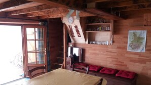 A wooden interior with a table and benches, a clock, shelves with glasses, and a map on the wall.