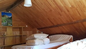 A cozy attic bedroom with wooden walls, a sloped ceiling, and a bed with white linens.