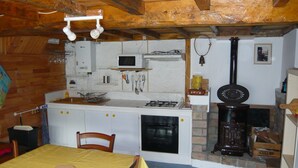 A compact kitchen with a gas stove, microwave, and a wood-burning stove.
