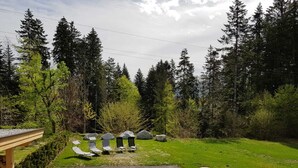 Área de pátio com mobiliário para área externa e vista para uma paisagem arborizada.